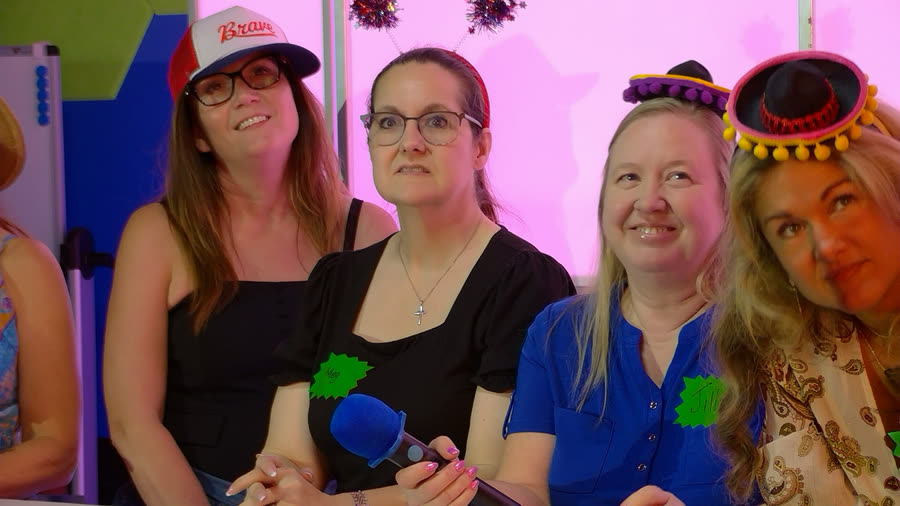 Four guests in party hats watching a round play out