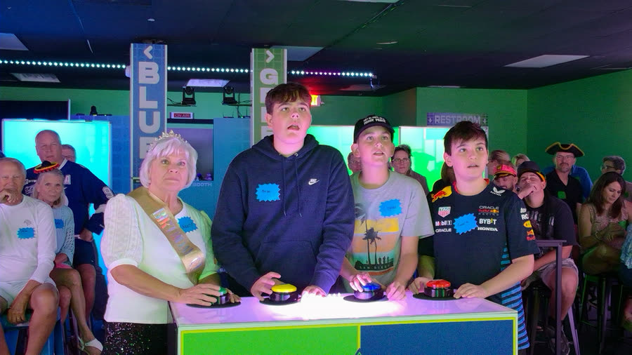 Four players at the buzzers with a seated audience behind them