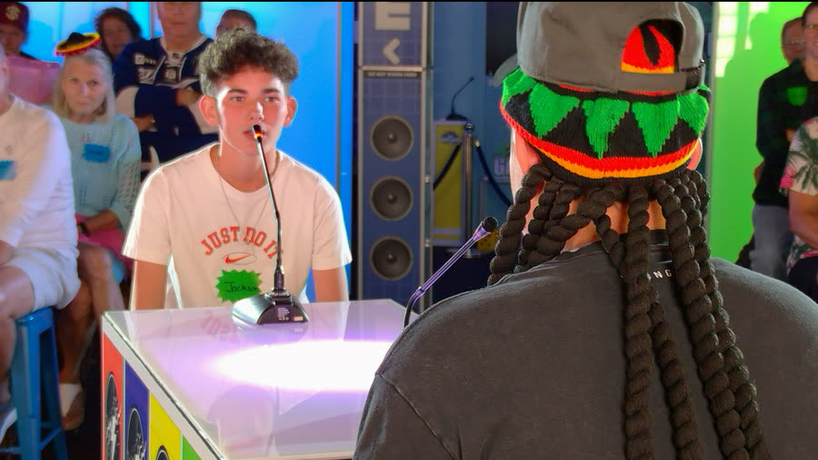 A player answering into the podium microphone while the host listens