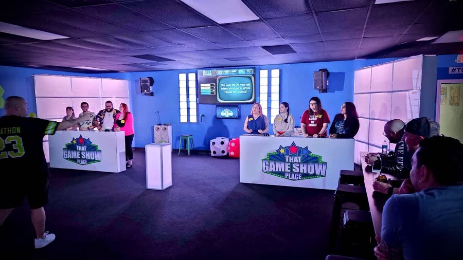 Both team podiums with players at the buzzers and a question on the screen