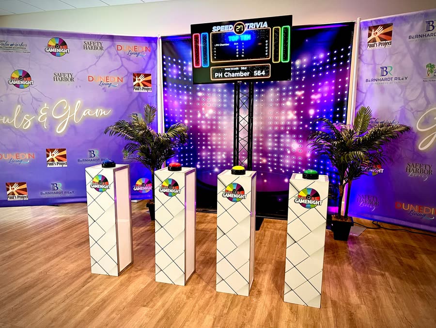 The travel rig set up in a function room with four podiums and buzzers facing a scoreboard screen